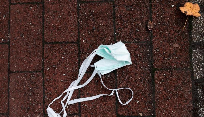 Auf einer Straße liegt ein Mund-Nasen-Schutz auf dem Boden. Auf einer Straße liegt ein Mund-Nasen-Schutz auf dem Boden.