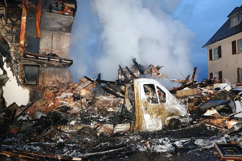 Ein ausgebrannter Kleinlaster steht vor den Trümmern eines Hauses. Nach einer mutmaßlichen Gasexplosion in dem Wohnhaus im Westen Stuttgarts wird ein Anwohner vermisst.