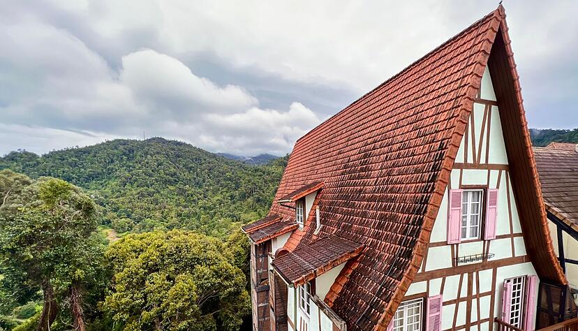 Hinter einem Fachwerkhaus in Colmar Tropicale ist der Dschungel der Berjaya Hills zu sehen.
