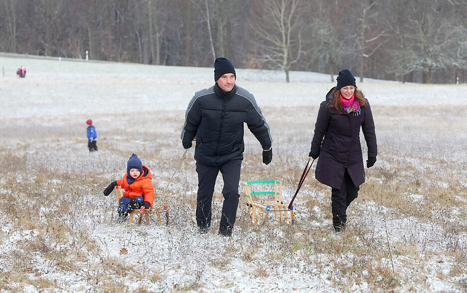 Kinder und Erwachsene genie&szlig;en Rodelspa&szlig; in der winterlichen Landschaft.