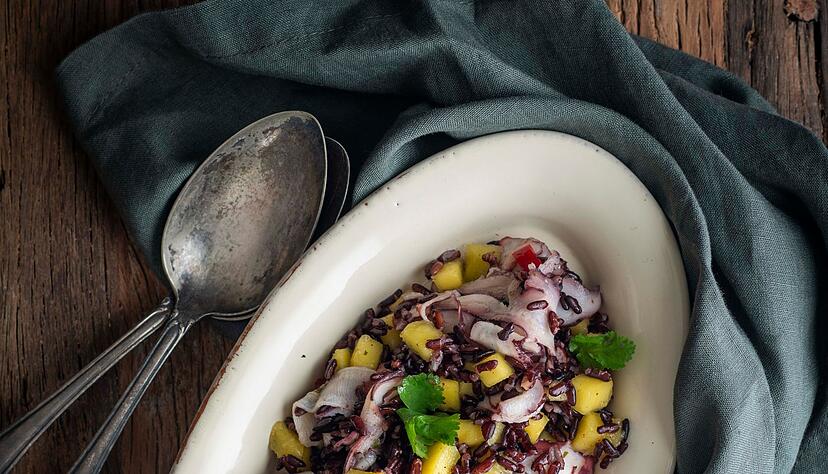 Wenn es mal etwas ganz Exotisches sein soll: Dieser schwarze Reissalat mit Mango und Oktopus sticht auf einer Mitbringfeier sicher heraus.
