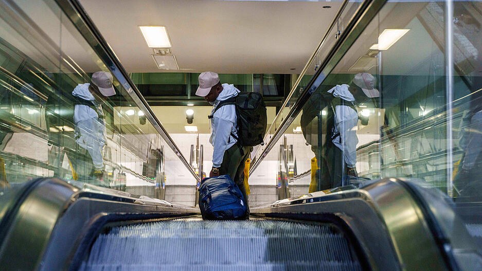 Ein Reisender steht mit seinem Gepäck am Flughafen Frankfurt auf der Rolltreppe. Ein Reisender steht mit seinem Gepäck am Flughafen Frankfurt auf der Rolltreppe.