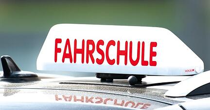 Ein Schild mit der Aufschrift «Fahrschule» ist auf einem Fahrschulauto befestigt.
