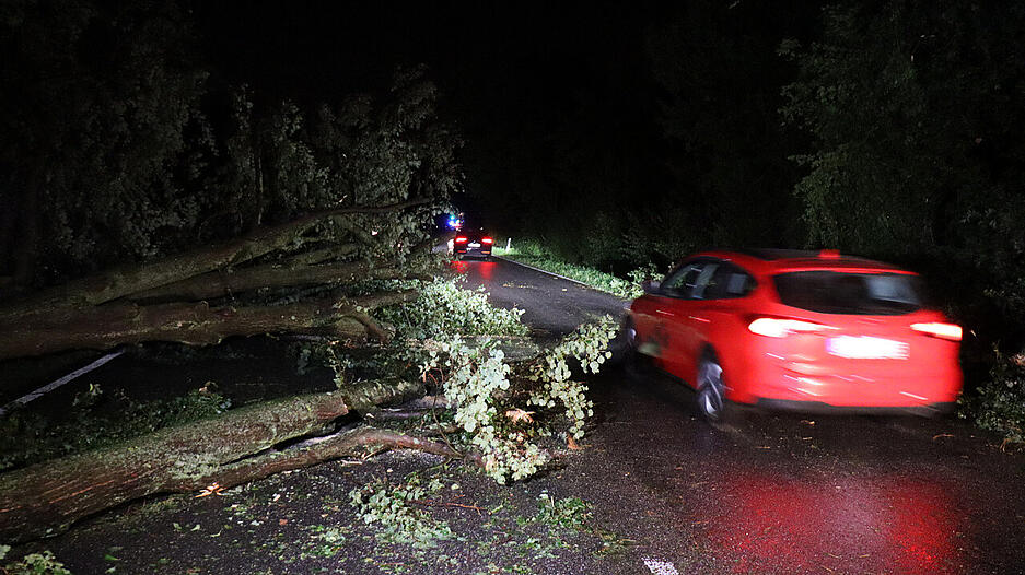 Ein Auto f&auml;hrt an einem umgest&uuml;rzten Baum vorbei im Landkreis Karlsruhe. Heftige Unwetter haben Stra&szlig;en &uuml;berflutet, Keller volllaufen und vor allem den Fluss Saalbach im Landkreis Karlsruhe extrem ansteigen lassen.