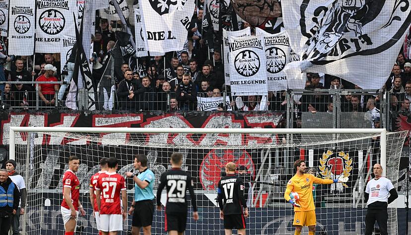 Torwart Trapp (2.v.r.) gestikuliert neben zwei Fans, die sich an die Pfosten gebunden haben.