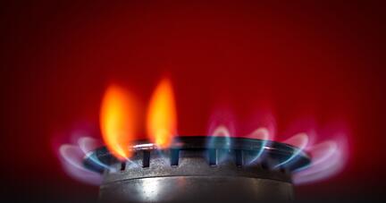 Die Flamme eines Gasherdes brennt in einer K&uuml;che.