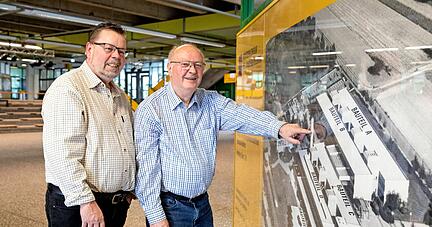 Der aktuelle Hausmeister Dirk Wolf (links) mit seinem Vater und Vorgänger Karl-Heinz Wolf in der Aula vor einer Luftaufnahme des Kreisberufsschulzentrums.
Foto: Andreas Veigel