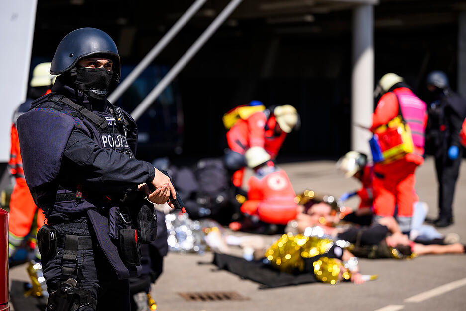 14.05.2024, Baden-Württemberg, Stuttgart: Ein Polizist steht vor einer Sammelstelle für verletzte bei einer praktische Übung einer Einsatzlage zur Fußball-Europameisterschaft. Von den insgesamt 51 Spielbegegnungen finden fünf Partien in der Stuttgarter MHP Arena statt. Die Einsatzkräfte der Polizei, der Rettungsdienste und anderer Behörden und Organisationen mit Sicherheitsaufgaben bereiten sich mit der Übung intensiv auf die Veranstaltungen vor. Foto: Tom Weller/dpa +++ dpa-Bildfunk +++