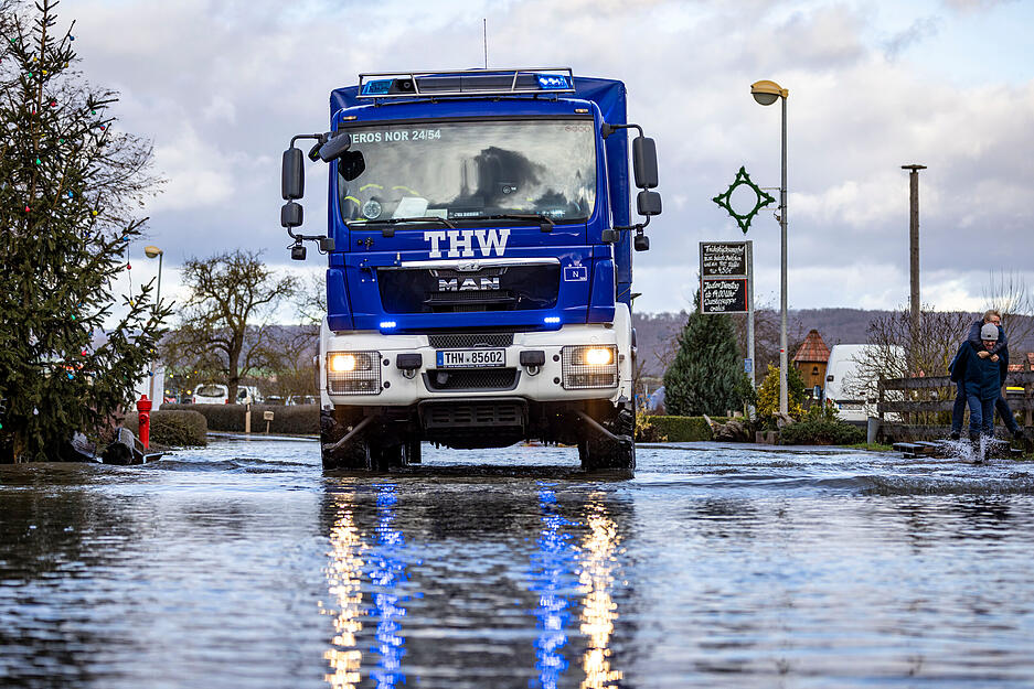 Ein Fahrzeug des THW fährt über eine überschwemmte Straße in Windehausen. Die Hochwasserlage in dem überfluteten und weitgehend geräumten Ort in Nordthüringen ist nach Einschätzung der Einsatzkräfte stabil. Entwarnung könne aber noch nicht gegeben werden.