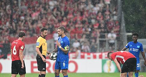 Schiedsrichter Michael Bacher (2.v.l.) muss das Spiel in Großaspach unterbrechen