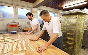 Aus l&auml;nglichen Teiglingen rollen Markus H&ouml;nnige (vorne) und sein Mitarbeiter Daniel Lohse lange Str&auml;nge, die sie dann zu Z&ouml;pfen flechten.