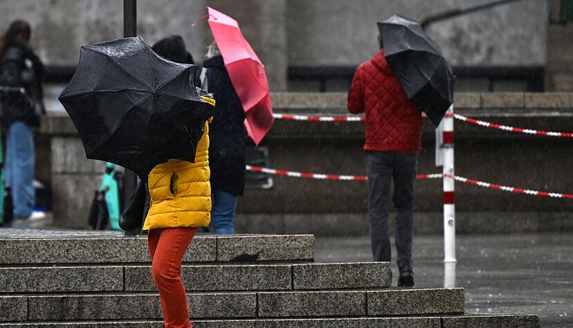 Passanten kämpfen in Köln mit dem Wind und ihren Regenschirmen. Zum Wochenbeginn ist das Wetter in Nordrhein-Westfalen weiter stürmisch und regnerisch.