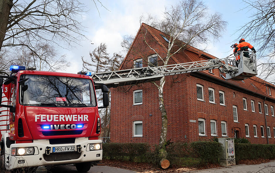 Die Feuererwehr ist mit einer Drehleiter im Einsatz, um einen Baum zu entfernen, der auf ein Haus gestürzt ist. Allein in Rostock musste die Feuerwehr wegen Sturmschäden zu Dutzenden Einsätzen ausrücken.