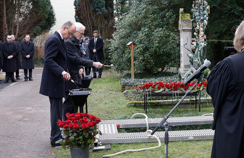 Nach dem Gottesdienst bei der Trauerfeier für Wolfgang Schäuble stehen Winfried Kretschmann (Bündnis 90/Die Grünen, r), Ministerpräsident von Baden-Württemberg, und Friedrich Merz (l), Bundesvorsitzender der CDU, am Grab auf dem Friedhof.
