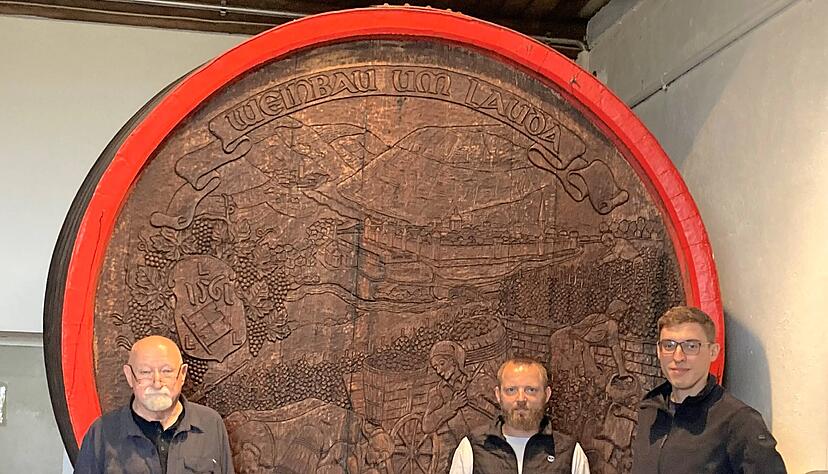 Fassbodenschnitzer Heinz Theobald, links, sein künftiger Nachfolger Sascha Bartmann und Winzer Johannes Sack vor dem größten Fass des Schnitzers. Das Weinfass erzählt von der Weinbautradition in der Region Lauda.
Foto: Julia Haaga Fassbodenschnitzer Heinz Theobald, links, sein künftiger Nachfolger Sascha Bartmann und Winzer Johannes Sack vor dem größten Fass des Schnitzers. Das Weinfass erzählt von der Weinbautradition in der Region Lauda.
Foto: Julia Haaga