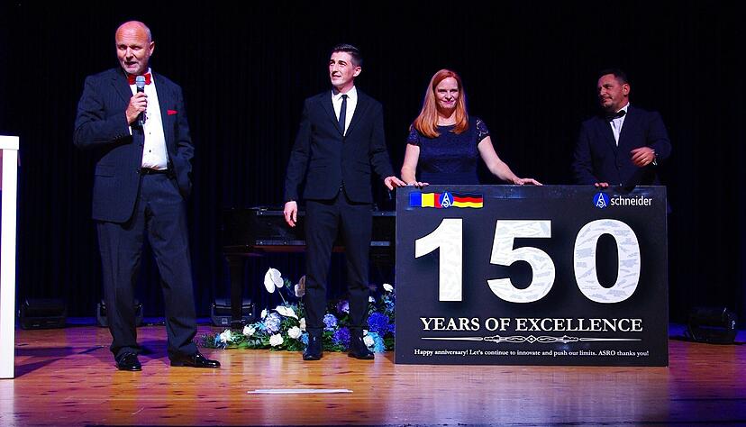 Gl&uuml;ckw&uuml;nsche auch aus Rum&auml;nien: Die Mitarbeiter des dortigen Schneider-Werks, angef&uuml;hrt von Verkaufsdirektor Mihai Tache (rechts), &uuml;berreichten eine gro&szlig;e Tafel an Gesellschafterin Christiane Jedlitzke und Gesch&auml;ftsf&uuml;hrer Franz Joachim Trasser.