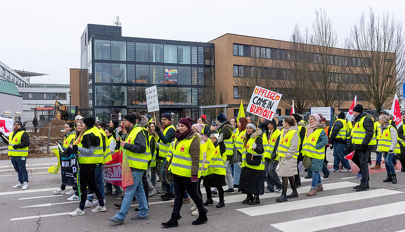 Mit Warnwesten und Schildern ausgestattet ziehen die streikenden Pflege-Mitarbeiter durch Heilbronn.