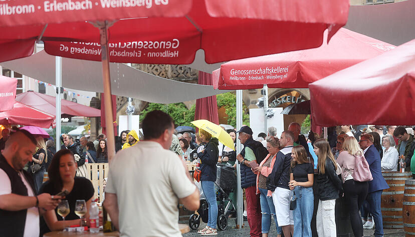 Weindorf-Besucher suchen unter Schirmen Schutz vor dem Regen.