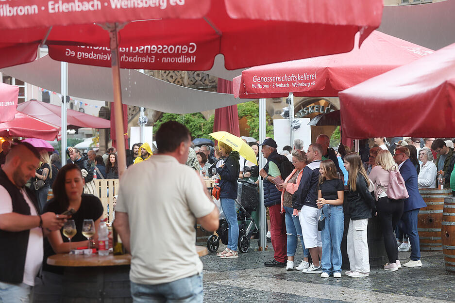 Weindorf-Besucher suchen unter Schirmen Schutz vor dem Regen.