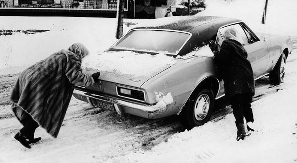 1968: Mit dem Auto ist es bei Schneeglätte schon so eine Sache. Selbst Damen werden im Ernstfall nicht geschont, wenn der fahrbare Untersatz wieder flott gemacht werden muss.