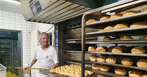 Bäckermeister Roland Bürk holt frisch gebackene Brötchen mit einem Holzschieber aus dem Ofen. Der Arbeitsschritt ist Teil der morgendliche Routine in der Backstube. Foto: Möllers Bäckermeister Roland Bürk holt frisch gebackene Brötchen mit einem Holzschieber aus dem Ofen. Der Arbeitsschritt ist Teil der morgendliche Routine in der Backstube. Foto: Möllers