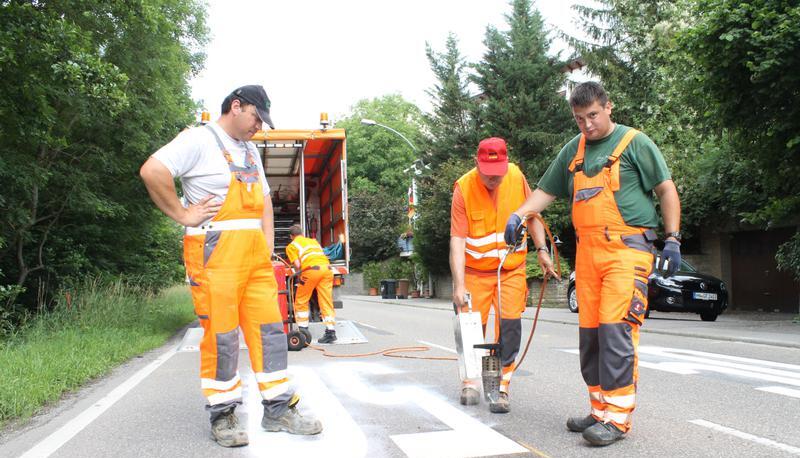 Kolonnenf&uuml;hrer J&ouml;rg Ulrich (links) und seine Kollegen von der Stra&szlig;enmeisterei Neuenstadt bringen die Zahlen aus Hei&szlig;plastik auf der Fahrbahn auf. 
Foto: Rolf Muth