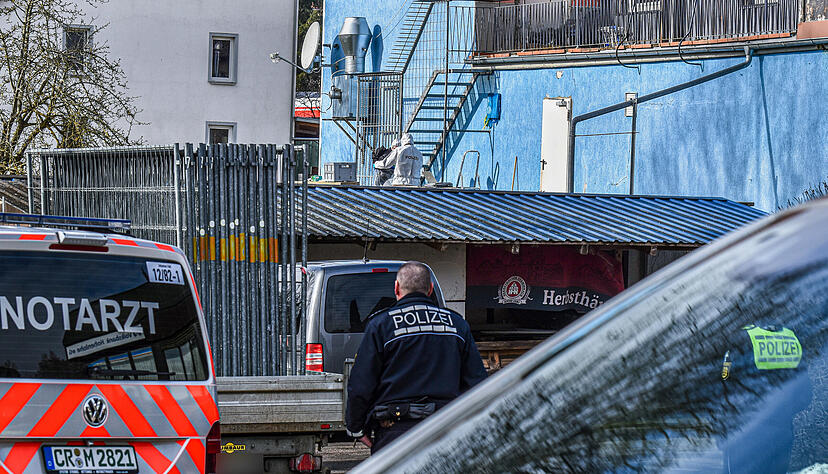 Polizisten in Spezialanz&uuml;gen (hinten) stehen bei der Spurensicherung an der R&uuml;ckseite eines Wohn- und Gesch&auml;ftshauses in Schrozberg, an dem ein Mann seine Frau erschossen haben soll.