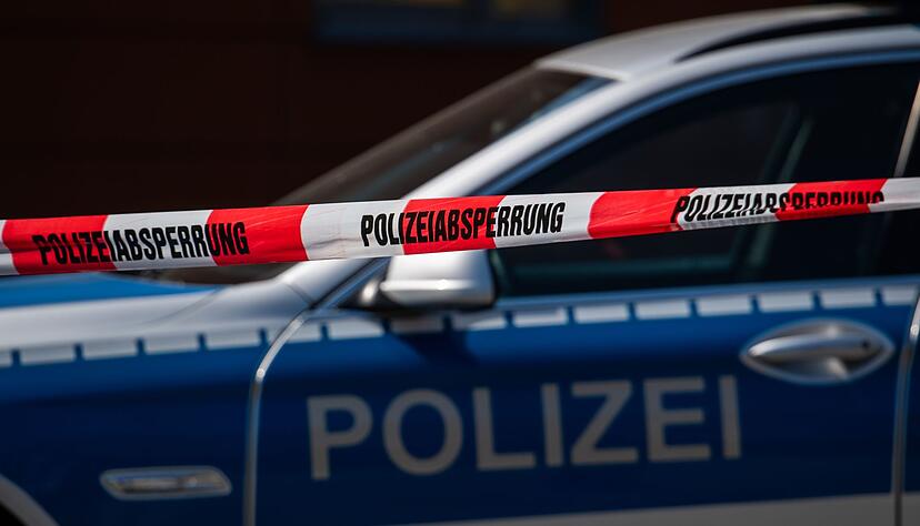 Ein Polizeiauto steht hinter einem Absperrband der Polizei.