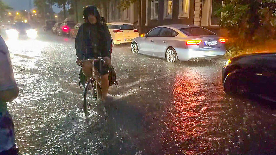 Ein Fahrradfahrer in Freiburg fährt über eine vom Regen überschwemmte Straße. Ein Fahrradfahrer in Freiburg fährt über eine vom Regen überschwemmte Straße.