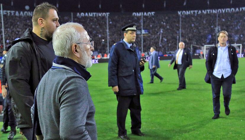 Iwan Savvidis (vorne), Besitzer und Pr&auml;sident des Fu&szlig;ballclubs Paok Saloniki, geht mit einer Waffe am G&uuml;rtel auf den Platz.