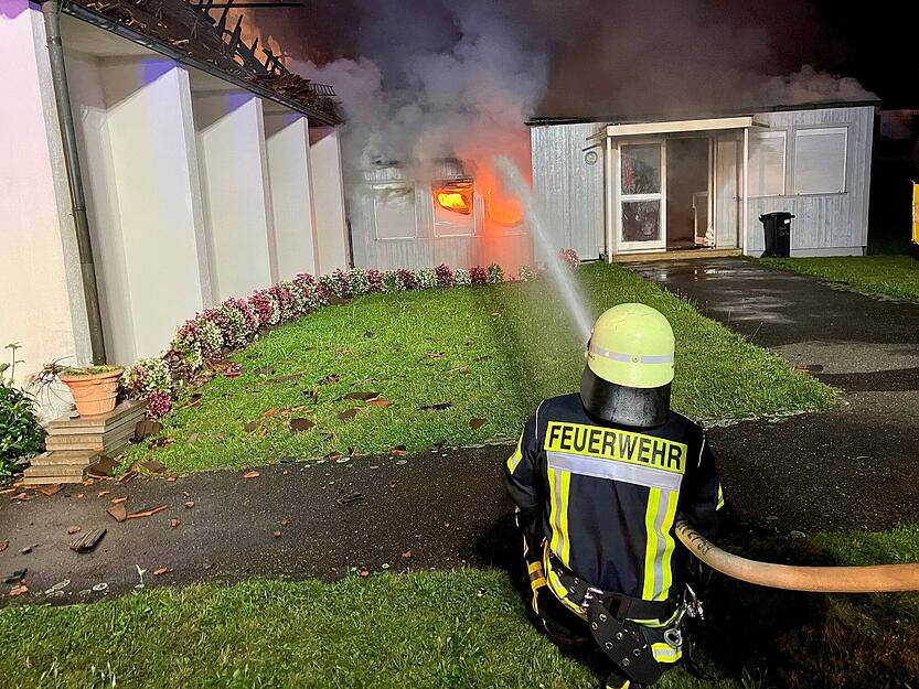 Ein Feuerwehrmann löscht Flammen, die aus der Kirche St. Josef in Widdern schlagen.