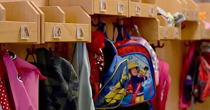 Jacken und Rucks&auml;cke h&auml;ngen in einer Kita an Haken im Flur.