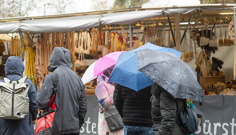 Mit Regenschirmen oder Kapuzen wagen sich einige Besucher &uuml;ber den Heilbronner Pferdemarkt am Samstag.