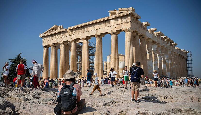 Touristen in Athen gehen an einem heißen Tag bei ihrem Besuch des Parthenon-Tempels auf dem Akropolis-Hügel. Touristen in Athen gehen an einem heißen Tag bei ihrem Besuch des Parthenon-Tempels auf dem Akropolis-Hügel.