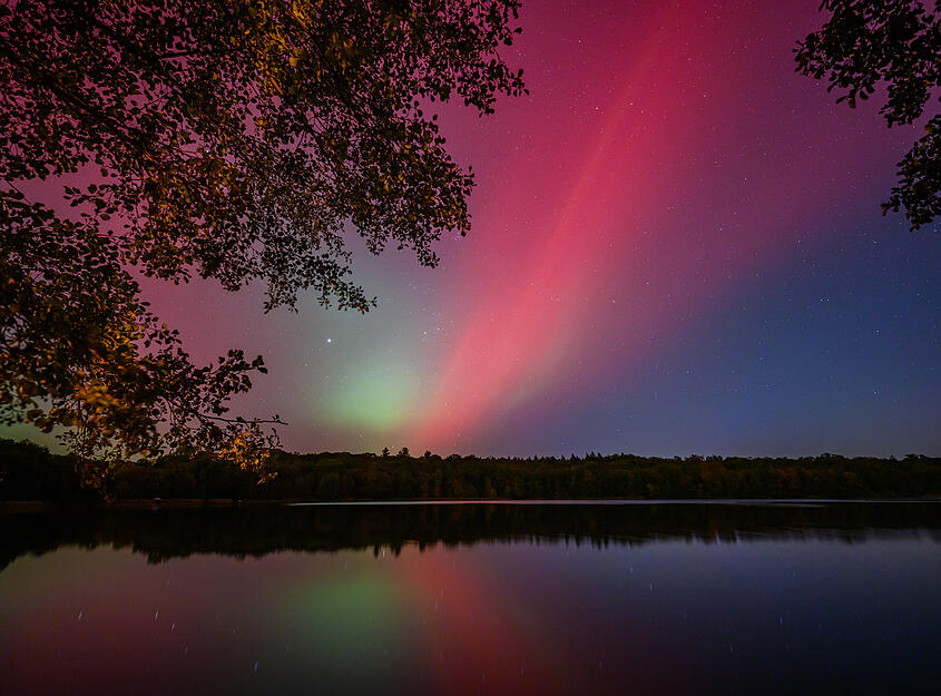 Polarlichter leuchten am Nachthimmel über dem Schwarzen See im östlichen Brandenburg.