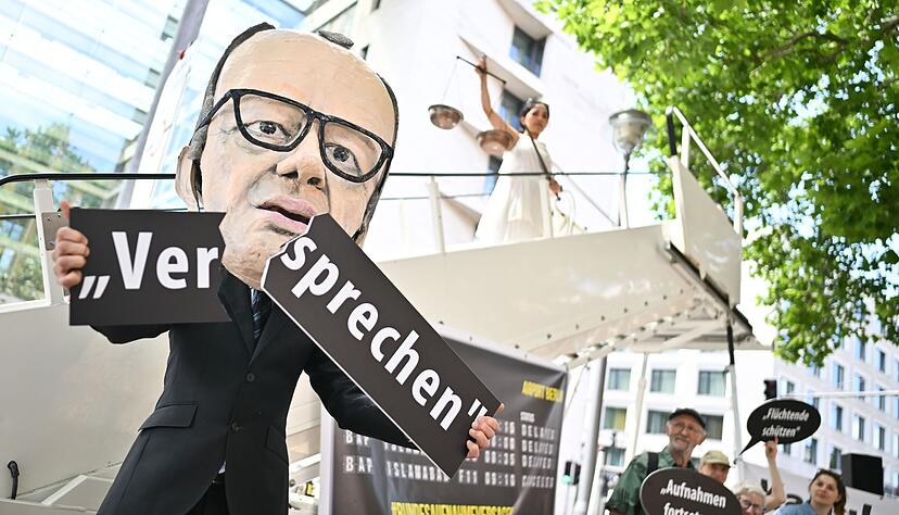 Ein Aktivist mit Merz-Maske zerbricht während einer symbolischen Protestaktion von Kabul Luftbrücke und Campact ein Schild mit der Aufschrift «Versprechen». Ein Aktivist mit Merz-Maske zerbricht während einer symbolischen Protestaktion von Kabul Luftbrücke und Campact ein Schild mit der Aufschrift «Versprechen».