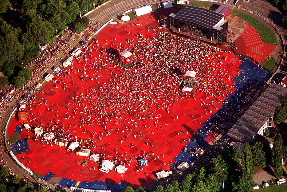 Im Jahr 2000 spielt Bryan Adams ein Konzert im Heilbronner Frankenstadion. Zum Schutz des Fußball-Rasens sind rote Plastikplanen vor dem Auftritt ausgelegt worden.