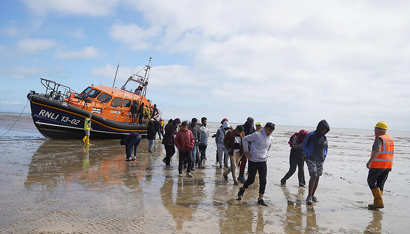 Eine Gruppe von Menschen, bei denen es sich vermutlich um Migranten handelt, wird von einem Rettungsboot an Land gebracht.