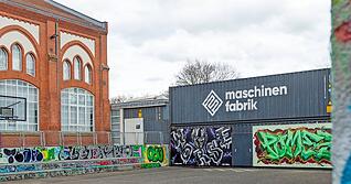 Die Sanierung der Maschinenfabrikhalle l&auml;sst auf sich warten. Zwecks L&auml;rmschutz wurden Container 2022 provisorisch zu einer Wand gestapelt.
