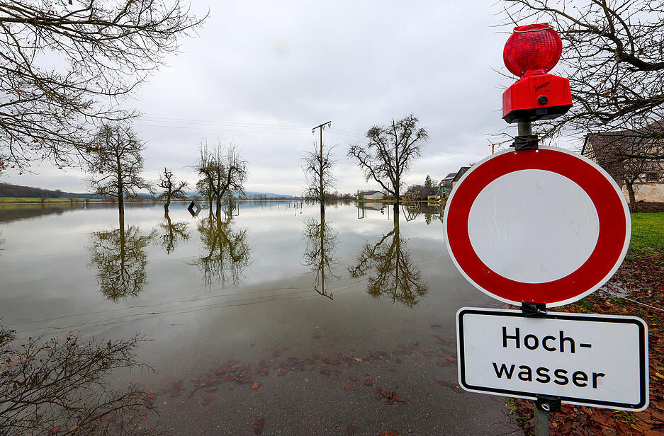 Hinter einem Durchfahrt verboten und Hochwasser-Hinweisschild, stehen bei Riedlingen Bäume im Wasser.