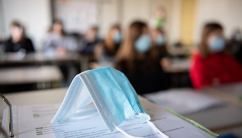 Ein Mund-Nasen-Schutz liegt im Unterricht auf Unterlagen. Ein Mund-Nasen-Schutz liegt im Unterricht auf Unterlagen.