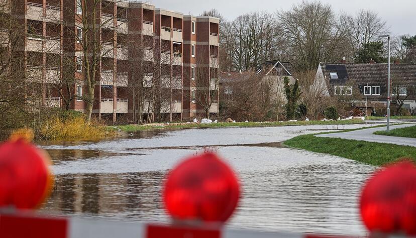 Sandsäcke liegen auf einem durchweichten Deich vor evakuierten Wohnhäusern in Lilienthal bei Bremen.