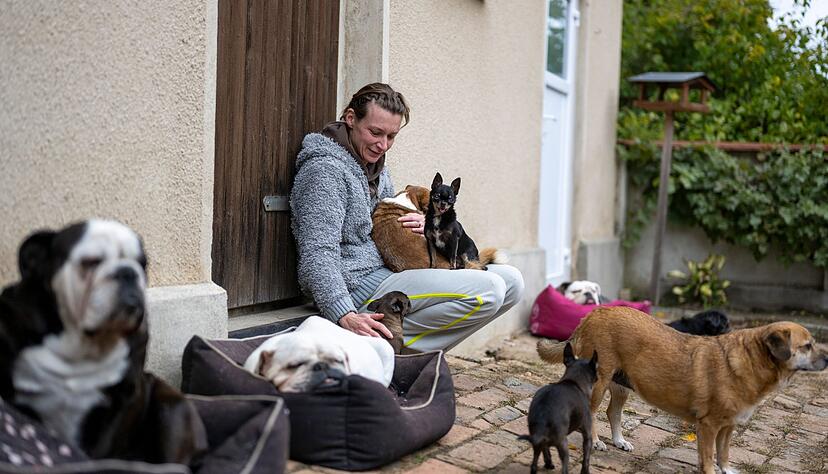 Stephanie Badura sitzt vor ihrem Haus und streichelt ihre Pflegehunde.