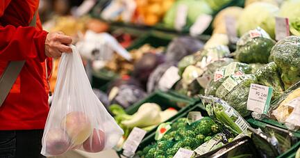 Eine Kundin steht in der Obst- und Gemüseabteilung eines Supermarkts.