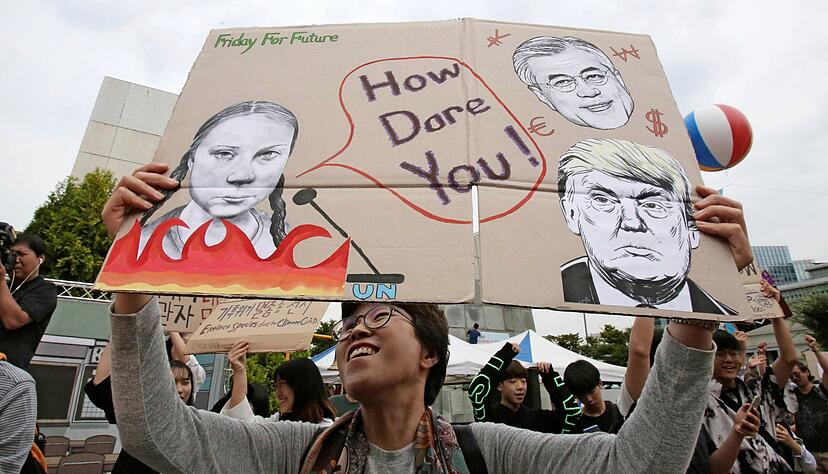In S&uuml;dkorea h&auml;lt im September 2019 ein junger Mann ein Plakat mit dem Portr&auml;t der schwedischen Klimaaktivistin Greta Thunberg in die Luft.   ???
Foto: dpa???  ???