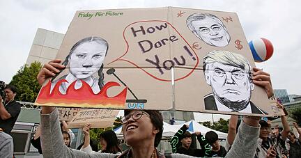 In S&uuml;dkorea h&auml;lt im September 2019 ein junger Mann ein Plakat mit dem Portr&auml;t der schwedischen Klimaaktivistin Greta Thunberg in die Luft.   ???
Foto: dpa???  ???