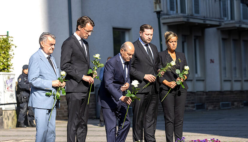 Herbert Reul (CDU, l-r), Innenminister von Nordrhein-Westfalen, Hendrik Wüst (CDU), Ministerpräsident von Nordrhein-Westfalen, Bundeskanzler Olaf Scholz (SPD), Tim Kurzbach (SPD), Bürgermeister von Solingen, und Mona Neubaur (Grüne), stellvertretende Ministerpräsidentin, legen Blumen an einer Kirche in der Nähe des Tatorts ab.