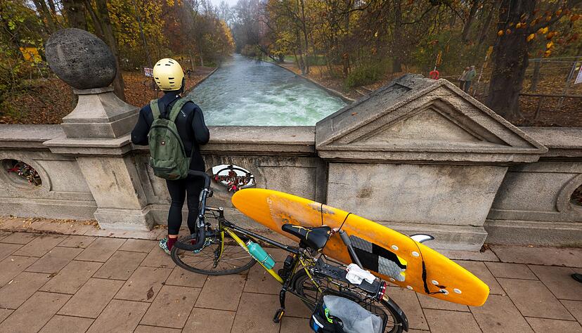 Ein Mann mit einem Surfboard an seinem Fahrrad schaut von einer Brücke auf die - nicht mehr vorhandene - Eisbachwelle im Englischen Garten. Ein Mann mit einem Surfboard an seinem Fahrrad schaut von einer Brücke auf die - nicht mehr vorhandene - Eisbachwelle im Englischen Garten.