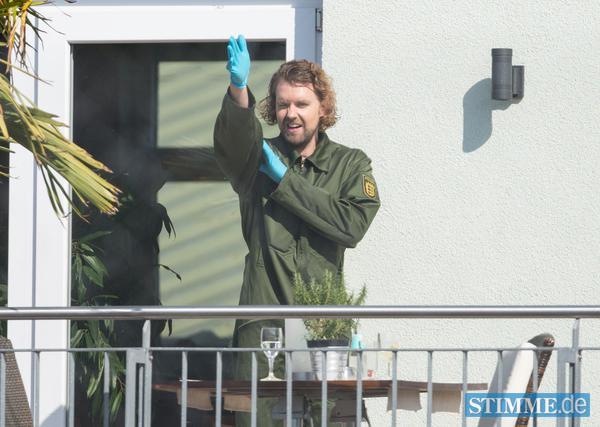 Ein Beamter der Spurensicherung zeigt am Mittwoch am Tatort auf einer Veranda mit seinem Arm die mögliche Schussrichtung einer Kugel. Der Täter hatte am Dienstag im Streit bei einer Eigentümerversammlung zwei Männer erschossen, fünf Menschen verletzt und sich dann selbst das Leben genommen.