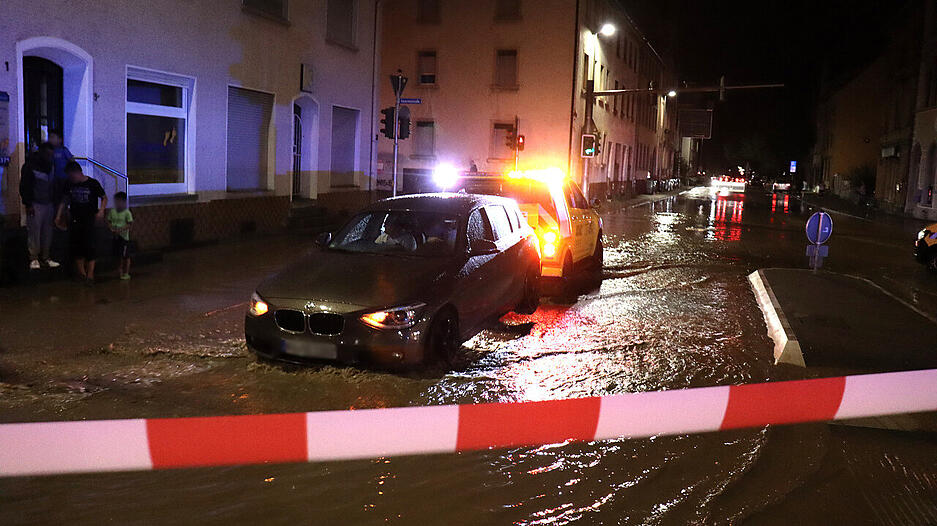 Hochwasser &uuml;berflutet im Landkreis Karlsruhe eine Stra&szlig;e w&auml;hrend ein Auto abgeschleppt wird.
